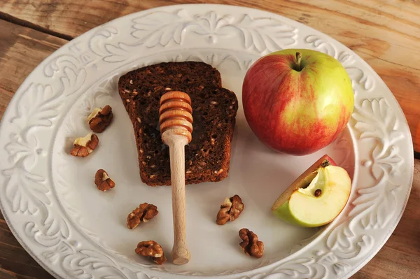 Prateleira de mel com pão, maçãs, nozes em um prato — Fotografia de Stock