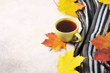 Sonbahar çay partisi. Akçaağaç yapraklarının arka planında bir fincan çay ve yün atkı.