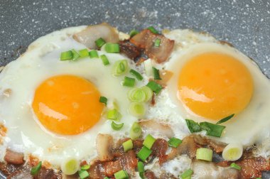 Kızarmış yumurta, domuz pastırması ve yeşil soğanlı kızartma tavası.