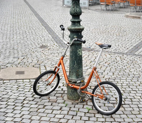 Оранжевый велосипед прикованный к столбу — стоковое фото