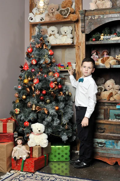 Juledreng omkring juletræ med gaver - Stock-foto