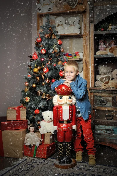 Christmas boy and the Nutcracker around Christmas tree with gift — Stock Photo, Image