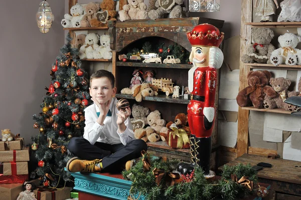 Christmas boy and the Nutcracker around Christmas tree with gift — Stock Photo, Image