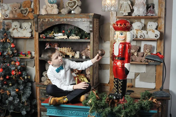 Christmas boy and the Nutcracker around Christmas tree with gift — Stock Photo, Image