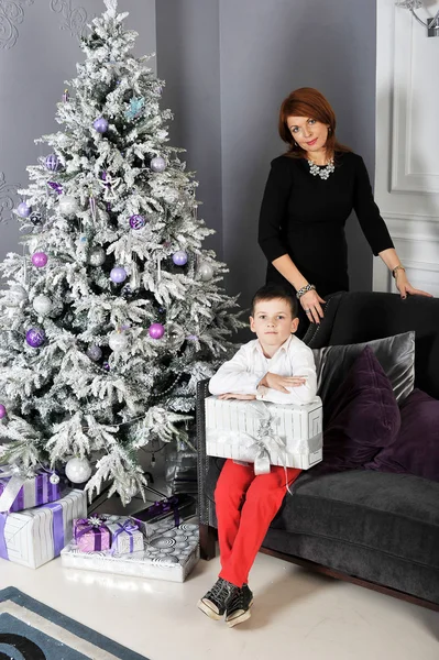 A little boy with a gift for his mother around the Christmas tre — Stock Photo, Image