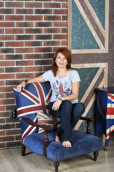 Menina sentada na mesa de cabeceira no fundo da bandeira Inglês — Fotografia de Stock