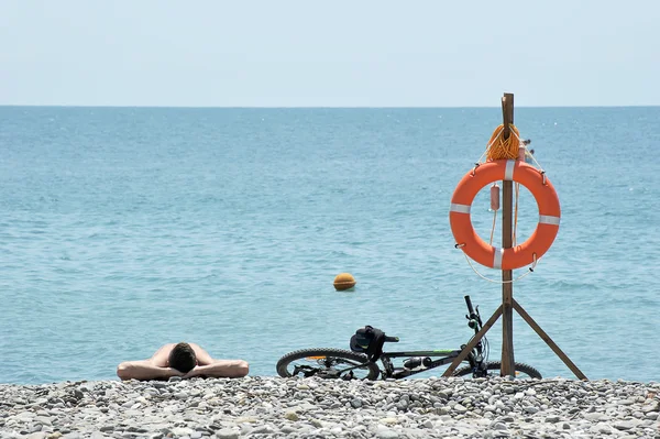 Człowiek leżący na kamienistej plaży — Zdjęcie stockowe