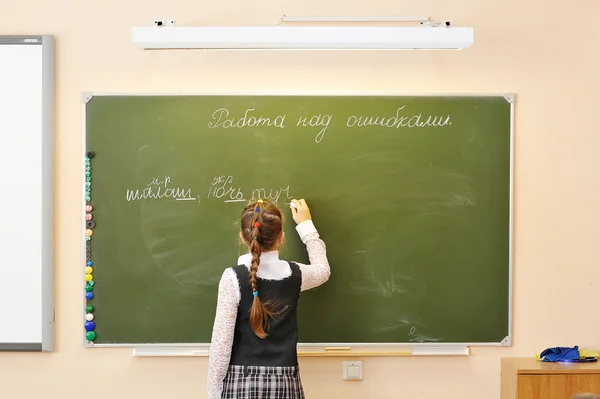 School girl writes in chalk on a blackboard. the inscription on — Stock Photo, Image