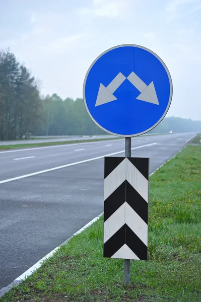Znak drogowy na szosie. strzałki wskazują kierunek m — Zdjęcie stockowe