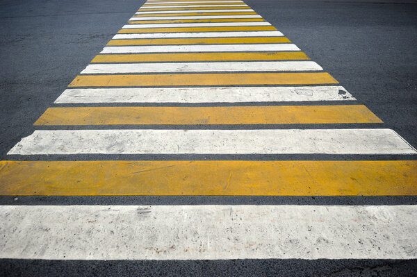 pedestrian crossing the road consists of white and yellow stripe