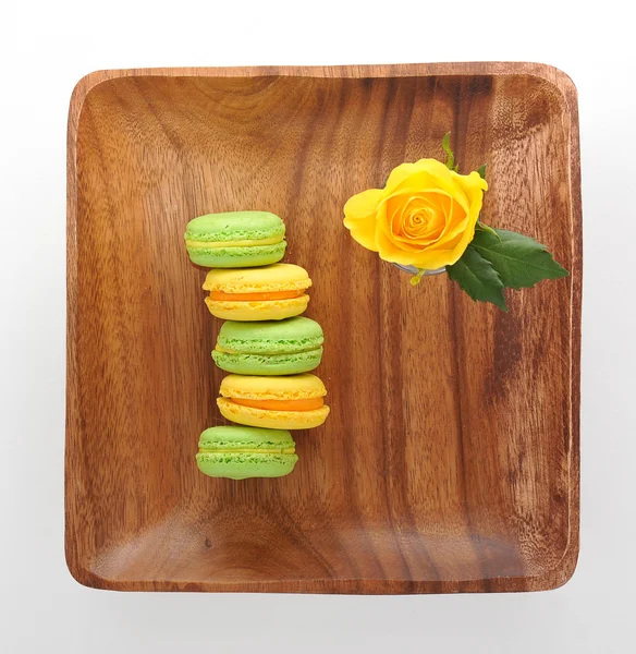 Macarons de sobremesa franceses populares e rosa amarela em uma bandeja de madeira — Fotografia de Stock