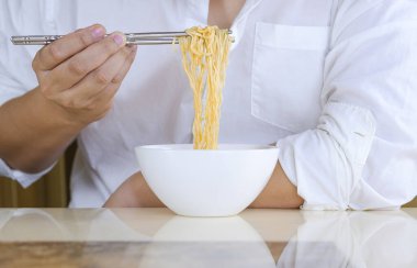 Beyaz gömlekli adamın elini gümüş çubuklarla kapayın ve evdeki beyaz kasede hazır erişte yiyin.