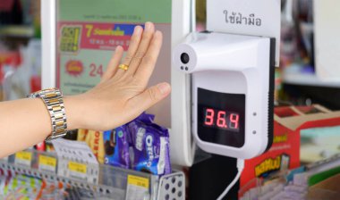 Samut Sakhon, Tayland - 13 Kasım 2020: Markette temas edilmeyen kızılötesi termometreyle vücut ısısını ölçen kadın müşteriye odaklan