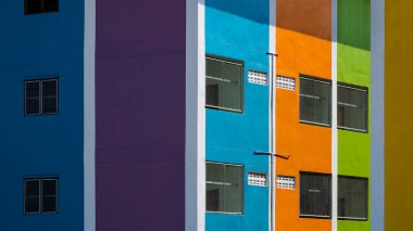 Renkli apartmanların yan duvarlarında güneş ışığı ve gölge var.