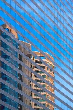 Yüksek ofis binasının dikey çerçevesindeki mavi cam duvar yüzeyindeki gökdelenin soyut yansıma deseni