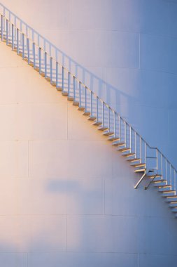 Güneş ışığı eğri kıvrımlı merdiven yüzeyinde depolama yakıt deposunun dikey çerçevesinde.