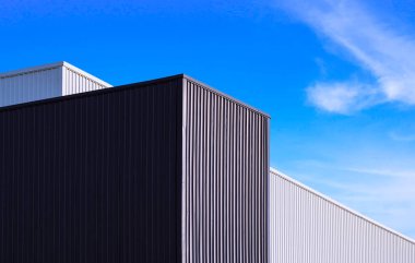 Mavi gökyüzü arka planına karşı siyah-beyaz kıvrımlı metal fabrika binalarının düşük açılı görüntüsü