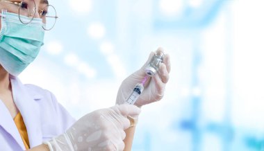 Kadın doktora odaklan. Elinde şırınga ve aşı şişesi olan tıbbi eldivenlerle hastane odasının arka planında bulanıklık olan enjeksiyona hazır ol.