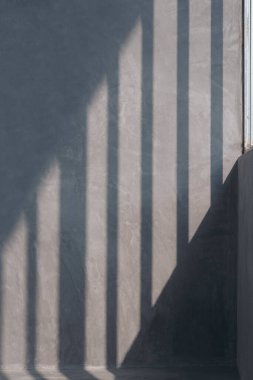 Ev inşaatı alanındaki beton duvar yüzeyindeki duvar iskeletinin güneş ışığı ve gölgesi dikey çerçevede.