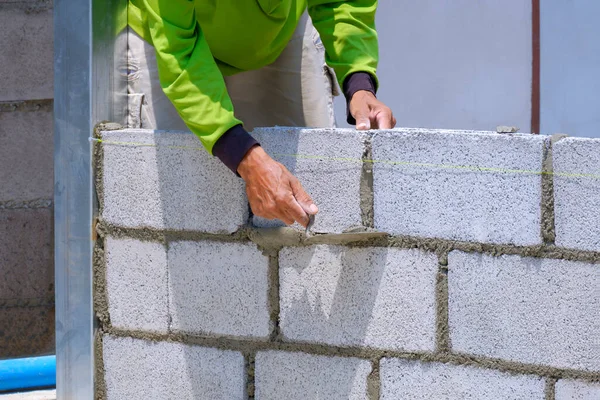 Cropped image of Asian builder worker building concrete block wall in house construction site