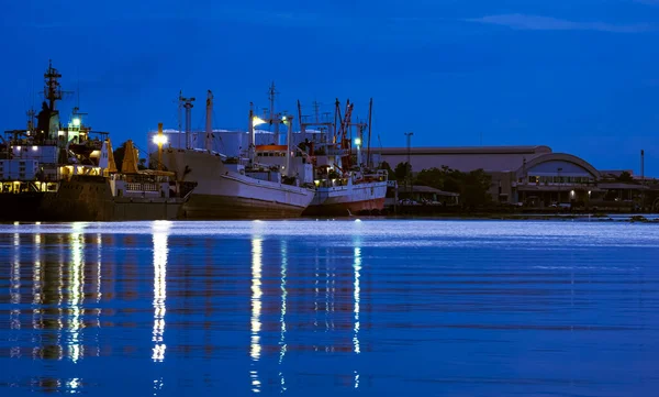 夜は川沿いの工業地帯の港に大型油送船や漁船が停泊 — ストック写真