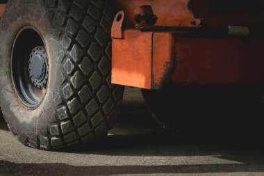 Turuncu yol silindirinin eski büyük tekerleğinin yüzeyinde koyu tonda güneş ışığı ve gölge.