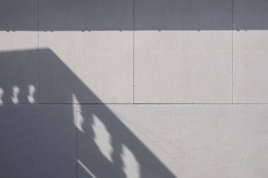 Gri alçıtaşı duvar zemininde güneş ışığı ve balkon gölgesi 