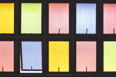 Sarı, yeşil, kırmızı ve mavi tonlarda geometrik desenli renkli vitray panelleri. Parlak ışık, canlı, sanatsal ve dekoratif bir mimari tasarım yaratır..