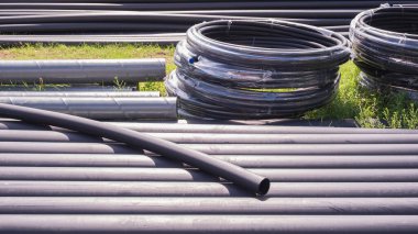 Yerdeki siyah HDPE borularından oluşan bir grup yeraltı su tesisatı işi için inşaat sahasında..