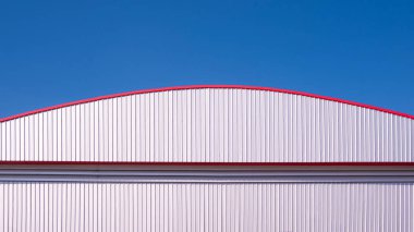 Büyük depo fabrikası endüstriyel dış yapı duvarı ve kubbe çatısı mavi gökyüzü zemininin altında koyu kırmızı süsleme süslemesi, fotokopi alanı ile ön görüş