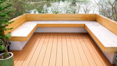 Modern ahşap güverte oturma alanı ve minimalist bir açık hava bahçesinde göl manzaralı yeşil alan.