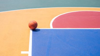 Renkli açık hava sahasında minimalist basketbol, canlı geometrik desenli, arka plan spor tasarımı için fotokopi alanı olan yüksek açılı görüş.