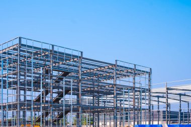 Modern endüstri ofis binasının metal iskeleti mavi gökyüzüne karşı endüstriyel fabrika şantiye alanı, perspektif yan görünüm