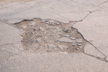 Kırık dokusu ve beton yol yüzeyinde çukurları olan eski ve kötü hasar görmüş sokak arkası.