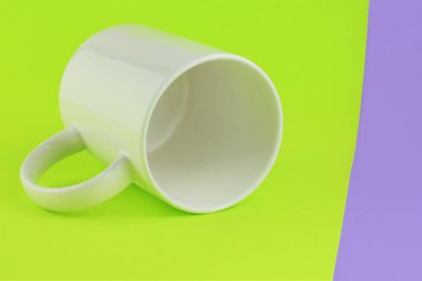 Beyaz porselen bardak, yakın plan, iki renkli arka plan. Metin için boşluk.