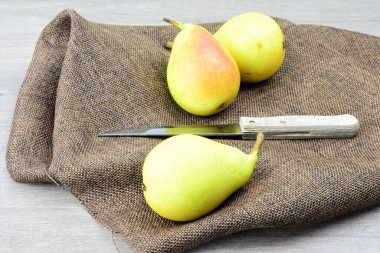 Ön planda armut, arka planda kumaş ve yanında bıçak.