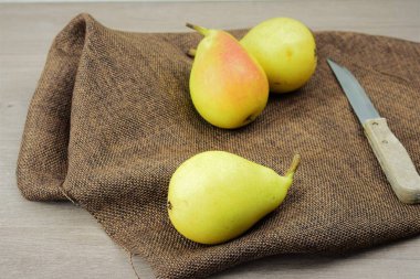 Ön planda armut, arka planda kumaş ve yanında bıçak.