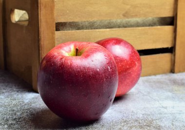 Macro, arkaplanda su damlaları olan kırmızı elma, ahşap kutu arka plan