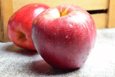 Macro, arkaplanda su damlaları olan kırmızı elma, ahşap kutu arka plan