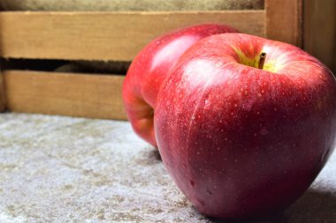 Kapatın. Işık taşına su damlatan kırmızı elma, tahta kutuda, metin için boşluk
