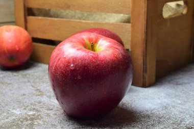 Macro, arkaplanda su damlaları olan kırmızı elma, ahşap kutu arka plan