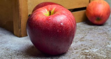 Kırmızı elma, ışık taşının üzerine su damlatıyor, ahşap kutuda.