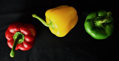 Siyah arka planda üç renkli biberler. Zirve görünümü.