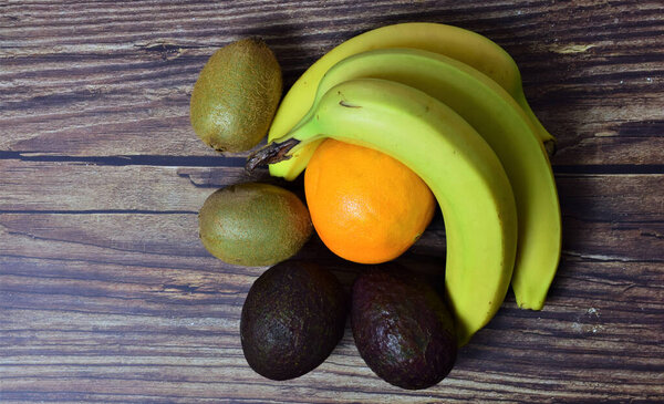 Тропические фрукты и апельсин, на деревенском коричневом столе.