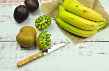 Beyaz tahtalarda çeşitli tropik meyveler, kiviler, muzlar ve avokadolar..