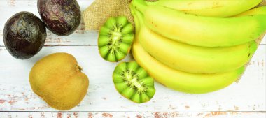 Beyaz tahtalarda çeşitli tropik meyveler, kiviler, muzlar ve avokadolar..