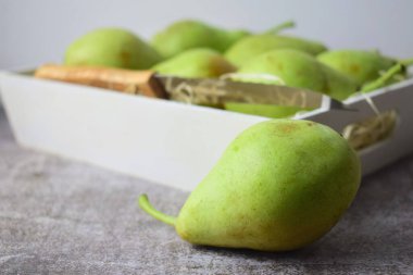 Altında daha fazla ünite olan yeşil armut, beyaz tahta bir kutunun içinde..