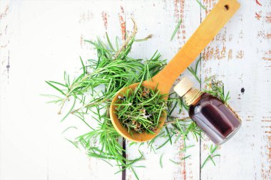 Zenith manzarası. Beyaz kırsal masada, ahşap kaşık ve cam kavanozda biberiye yaprakları.