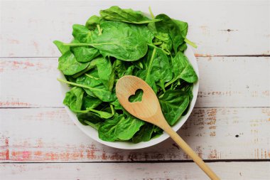 Sağlıklı yiyecekler, sebzeler, büyük beyaz bir kasede taze ıspanak yaprakları. Zirve görünümü.