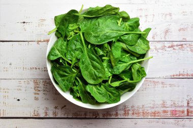 Sebze arkaplan, beyaz kasede taze ıspanak, beyaz sade ahşap, sağlıklı yiyecekler..